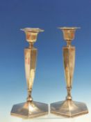 A PAIR OF HALLMARKED SILVER WEIGHTED HEXAGONAL TALL TABLE CANDLESTICKS. APPROX HEIGHT 25cms.