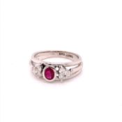 A 14ct WHITE GOLD RUBY AND DIAMOND RING. THE CENTRAL RUBY OVAL CUT IN A RUBOVER SETTING, APPROX
