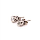TWO DIAMOND EAR STUDS EACH SET IN A SIX CLAW WHITE SETTING. THE FIRST DIAMOND BRILLIANT CUT WITH