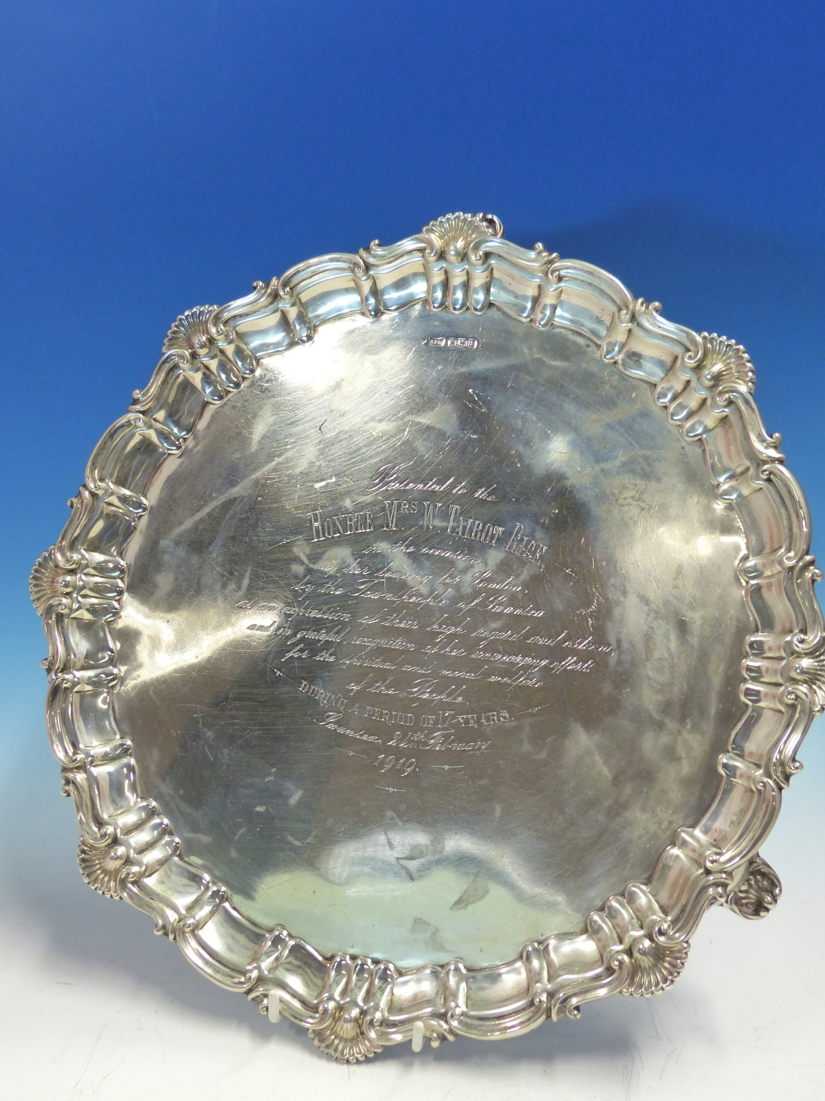 AN ANTIQUE HALLMARKED SILVER PRESENTATION WINE TRAY WITH FLUTED AND SHELL RIM AND THREE FEET.DATED