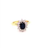 AN 18ct GOLD SAPPHIRE AND DIAMOND CLUSTER RING. THE OVAL CUT CLAW SET SAPPHIRE SURROUNDED BY A