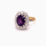 AN 18ct GOLD AMETHYST AND DIAMOND CLUSTER RING. THE OVAL CENTRAL AMETHYST CLAW SET SURROUNDED BY A