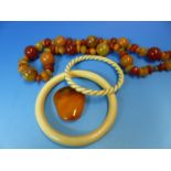 AN IVORY AND GOLD TWISTED BANGLE, A FURTHER IVORY BANGLE, AN AMBER PENDANT AND AN IRREGULAR ROW OF