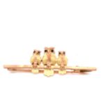 A 9ct GOLD OWL BAR BROOCH. THREE GRADUATED OWLS ARE SAT UPON THE GOLD BAR, EACH OWL WITH A TWO