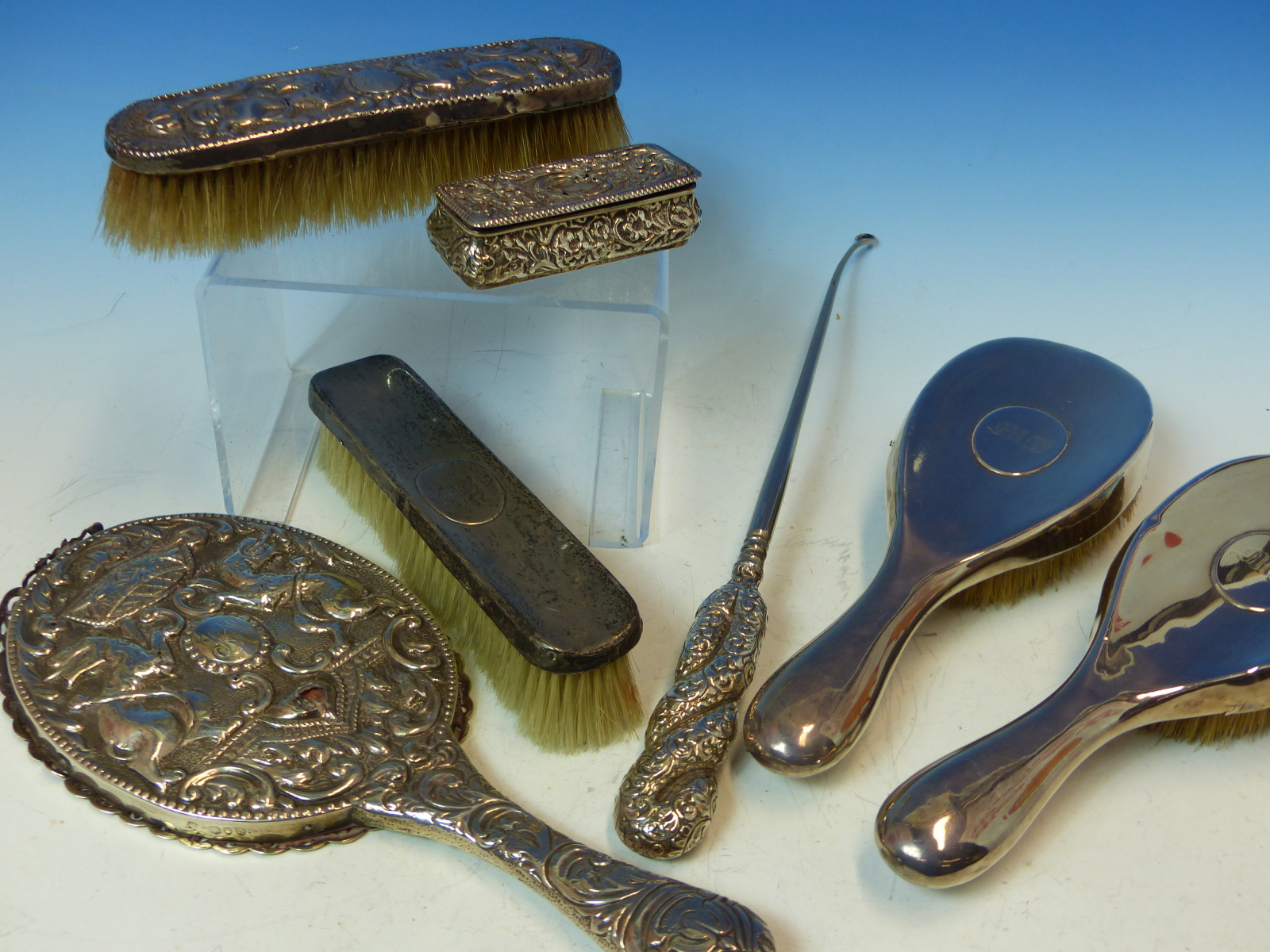 A HALLMARKED SILVER THREE PIECE DRESSING TABLE SET, A FURTHER REPOUSSE DECORATED MIRROR AND BRUSH, A