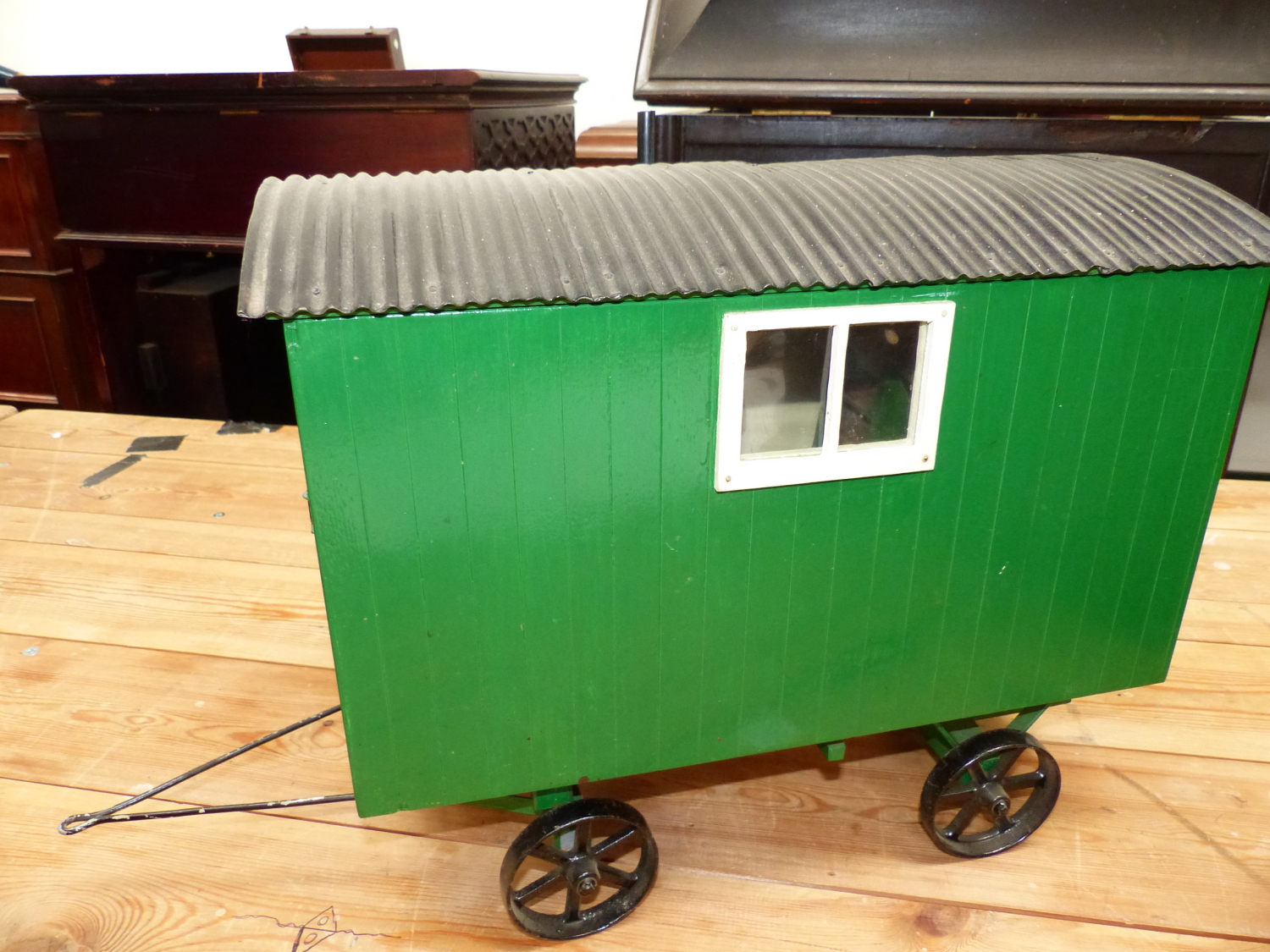 A SCALE MODEL GREEN PAINTED SHEPHERDS WAGON WITH BLACK WHEELS AND CORRUGATED IRON ROOF OVER A FITTED