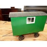 A SCALE MODEL GREEN PAINTED SHEPHERDS WAGON WITH BLACK WHEELS AND CORRUGATED IRON ROOF OVER A FITTED