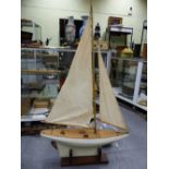 A MID 20th.C. RIGGED POND YACHT WITH WHITE/GREY HULL AND WEIGHTED KEEL ON MAHOGANY STAND.