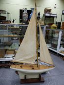 A MID 20th.C. RIGGED POND YACHT WITH WHITE/GREY HULL AND WEIGHTED KEEL ON MAHOGANY STAND.