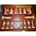 A 1950S CARVED AND PAINTED WOOD CHESS SET HOUSED IN A WOODEN CASE, THE PIECES CARVED AS FIGURES IN