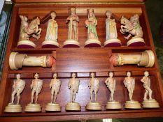 A 1950S CARVED AND PAINTED WOOD CHESS SET HOUSED IN A WOODEN CASE, THE PIECES CARVED AS FIGURES IN