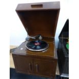AN OAK CASED EMG MARK IV WIND UP GRAMOPHONE, THE DOORS BELOW THE TURNTABLE OPENING TO REVEAL A BLACK