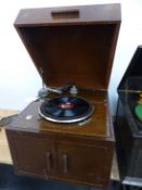 AN OAK CASED EMG MARK IV WIND UP GRAMOPHONE, THE DOORS BELOW THE TURNTABLE OPENING TO REVEAL A BLACK
