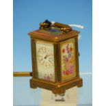 A MINIATURE CARRIAGE TIME PIECE THE BRASS CASE WITH FLOWER PAINTED PORCELAIN SIDES. H 6.5cms.