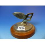 A MAHOGANY MOUNTED CHROME PLATED BENTLEY LOGO TOPPED RADIATOR CAP.