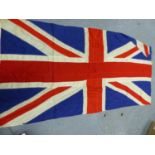 A UNION FLAG WITH ROPE SUSPENSION WITH WOODEN TOGGLE ENDS TO ONE SIDE
