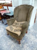 AN ANTIQUE WING BACK ARMCHAIR ON CARVED OAK FORELEGS.