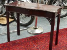 A GEORGIAN MAHOGANY TABLE, THE SERPENTINE FRONT EDGE CARVED WITH RIBBON AND FLOWER HEADS ABOVE A