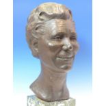 LOUISA BOLT, 1971, A BRONZE HEAD OF A SMILING LADY SUPPORTED ON VARIEGATED GREEN STONE PLINTH. H