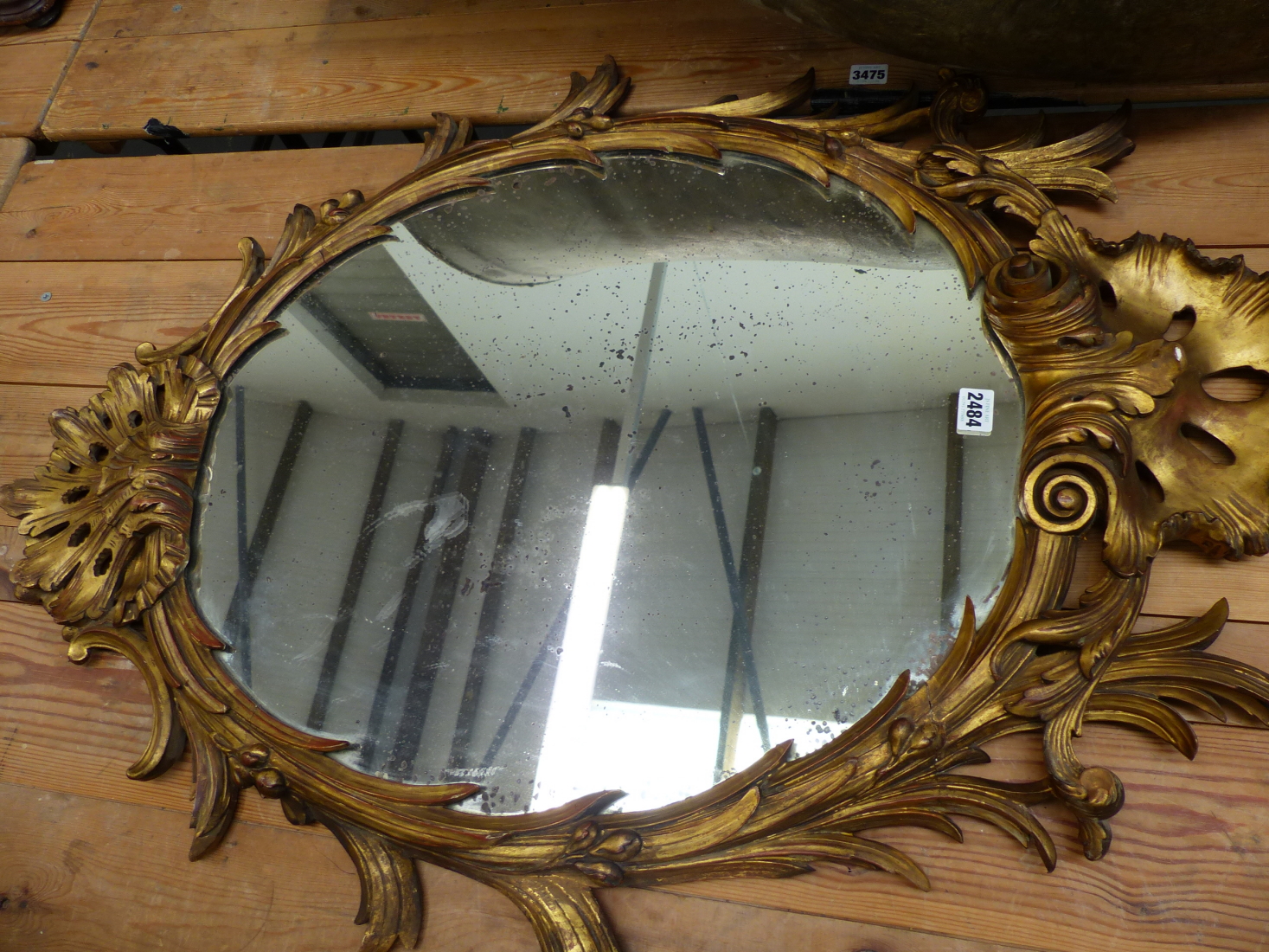 A CARVED GILTWOOD OVAL WALL MIRROR IN THE GEORGIAN TASTE.