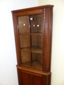 AN EARLY 20th.C.OAK FLOOR STANDING CORNER CABINET WITH CARVED DECORATION, SIX PANE GLAZED UPPER OVER