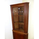 AN EARLY 20th.C.OAK FLOOR STANDING CORNER CABINET WITH CARVED DECORATION, SIX PANE GLAZED UPPER OVER