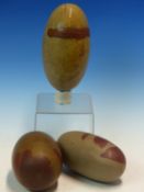 A COLLECTION OF THREE INDIAN RIVER POLISHED OATMEAL AND LIVER RED LINGAM STONES, THE LARGEST. W