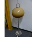 A CHROME STANDARD LAMP, THE COLUMN ON CIRCULAR FOOT, THE SHADE OF MUSHROOM SHAPE AND COLOUR,