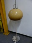 A CHROME STANDARD LAMP, THE COLUMN ON CIRCULAR FOOT, THE SHADE OF MUSHROOM SHAPE AND COLOUR,