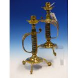 A PAIR OF BRASS CANDLESTICKS SUPPORTED BY VICTORIAN SWORD HANDLES, THE CIRCULAR BASES EACH ON