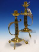 A PAIR OF BRASS CANDLESTICKS SUPPORTED BY VICTORIAN SWORD HANDLES, THE CIRCULAR BASES EACH ON
