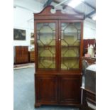 A GEORGIAN CARVED MAHOGANY BOOKCASE CABINET, SCROLL BROKEN PEDIMENT ABOVE GLAZED DOORS, PANELLED