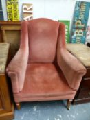 AN EDWARDIAN FIRESIDE ARMCHAIR ON SQUARE TAPERED LEGS WITH BRASS CASTERS.