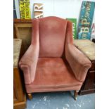 AN EDWARDIAN FIRESIDE ARMCHAIR ON SQUARE TAPERED LEGS WITH BRASS CASTERS.