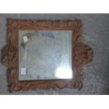 A RECTANGULAR MIRROR WITHIN A PINE FRAME CARVED WITH FOLIAGE, A MASK AT ITS BASE. 42.5 x 34.5cms.