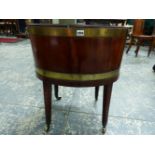 AN ANTIQUE BRASS BOUND MAHOGANY OVAL WINE COOLER ON STAND. BRASS CASTERS AND HANDLES. H. 67 x W.