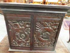 AN OAK TABLE TOP CABINET, THE DRAGON CARVED DOORS OPENING TO REVEAL THREE PIGEON HOLES EACH ABOVE