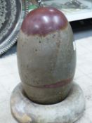 AN INDIAN RIVER POLISHED LINGAM STONE, THE OLIVE GREEN STONE WITH A LIVER RED CAP AND MARKINGS.