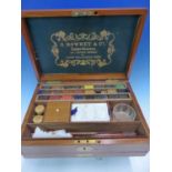 A ROWNEY MAHOGANY PAINT BOX COMPLETE WITH CAKES OF PAINT, TWO PALETTES, GLASS WATER BOWL, BRUSHES