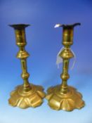 A PAIR OF 18th C. BRASS CANDLESTICKS WITH PUSHER EJECTORS WITHIN FEET SHAPED WITH FOUR STRAPS