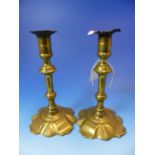 A PAIR OF 18th C. BRASS CANDLESTICKS WITH PUSHER EJECTORS WITHIN FEET SHAPED WITH FOUR STRAPS