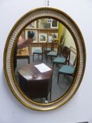 AN OVAL MIRROR WITHIN GILT BEAD AND FLUTED WHITE BANDS ON THE GILT EDGED FRAME. H 80 x 62.5cms.