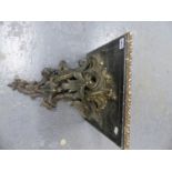 A CARVED WOOD AND GESSO ROCOCO FOLIAGE SUPPORTED SQUARE WALL BRACKET, NOW PAINTED BLACK WITH GILT