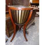 AN EDWARDIAN BRASS LINED MAHOGANY PLANTER WITH STRAP SIDES BELOW THE CIRCULAR TOP AND ON THREE