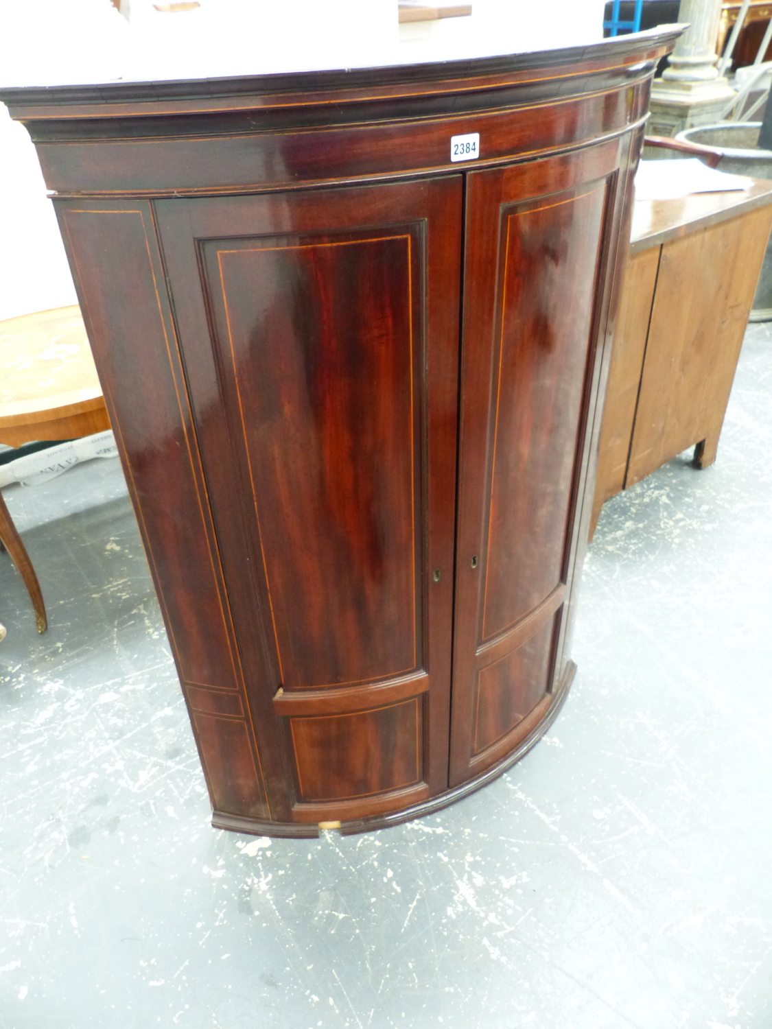 A MAHOGANY BOW FRONT CORNER CUPBOARD, THE TWO PANELS TO EACH DOOR WITH LINE INLAY. W 89 xD 55.5 x