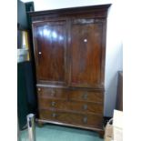 A LATE GEORGIAN MAHOGANY LINEN PRESS FITTED WITH FOUR SLIDES ENCLOSED BY PANEL DOORS OVER TWO