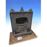 A SCARCE VICTORIAN CAST IRON MINIATURE SALESMAN'S SAMPLE OF A FIREPLACE HEARTH MOUNTED ON WOOD BASE.