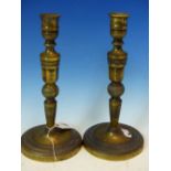 A PAIR OF ANTIQUE FRENCH BRASS EMPIRE STYLE CANDLESTICKS, ENGRAVED DECORATION. H. 26cms.