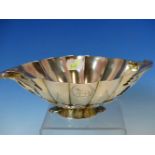 A WHITE METAL FLUTED LEAF FORM FOOTED BOWL WITH SCROLL HANDLES. ENGRAVED WITH ARMORIAL CRESTS. W.