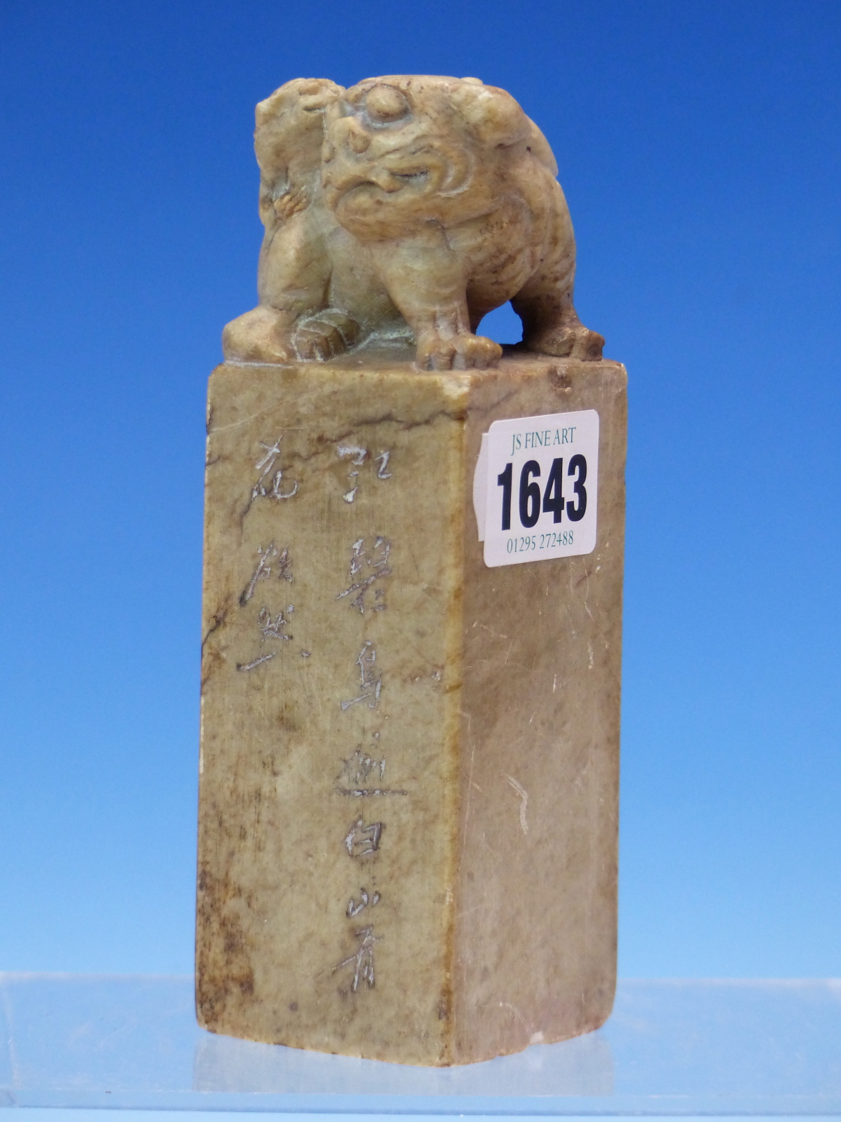 A CHINESE SOAPSTONE SEAL SURMOUNTED BY A BUDDHIST LION, AN INSCRIPTION TO ONE SIDE, THE BASE CUT